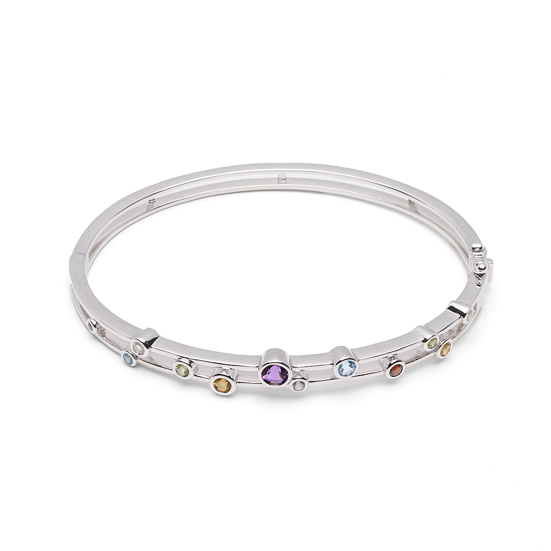 A silver-toned hinged bangle bracelet featuring a row of small, round, multicolored gemstones set along the front, displayed on a clean white background.