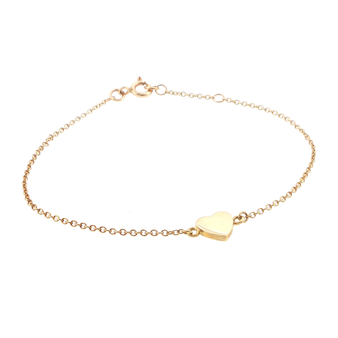 Gold bracelet with a heart-shaped charm on a white background